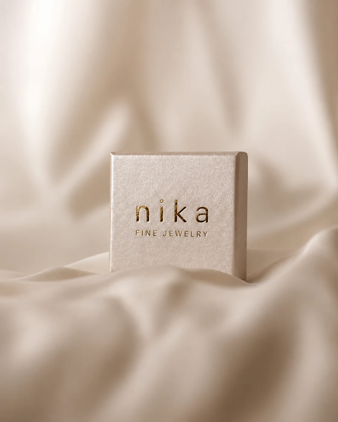 Nika Fine Jewelry — zlatá razba loga na svetlom obale